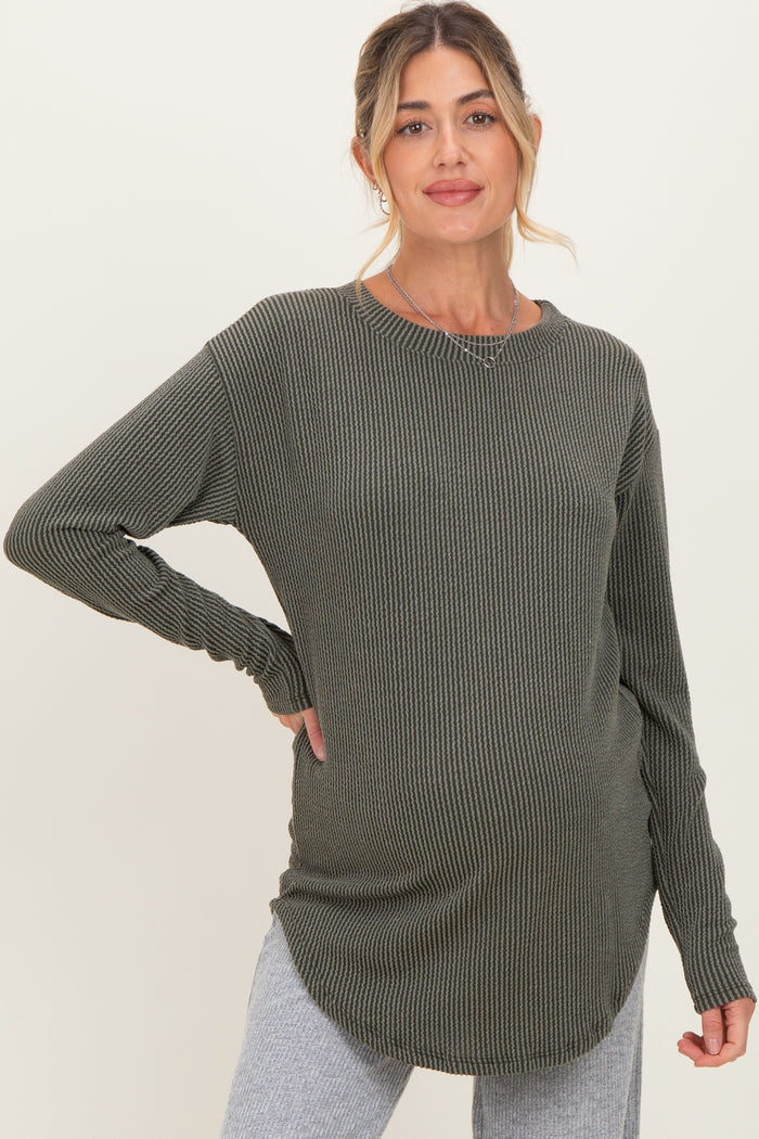 woman wearing a dark green long sleeve maternity top with a ribbed texture and a visible baby bump