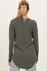 woman wearing a dark green ribbed maternity top with a longer back hem and long sleeves