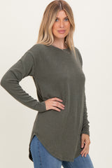 woman wearing a dark green ribbed long sleeve top with a curved hem and relaxed fit