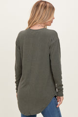 woman wearing a dark green ribbed long sleeve top with a curved hem, styled with blue jeans