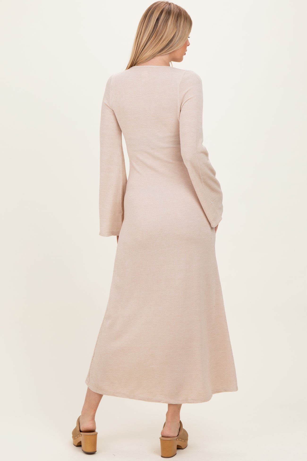 woman wearing a long sleeve beige ribbed maxi dress, viewed from the back