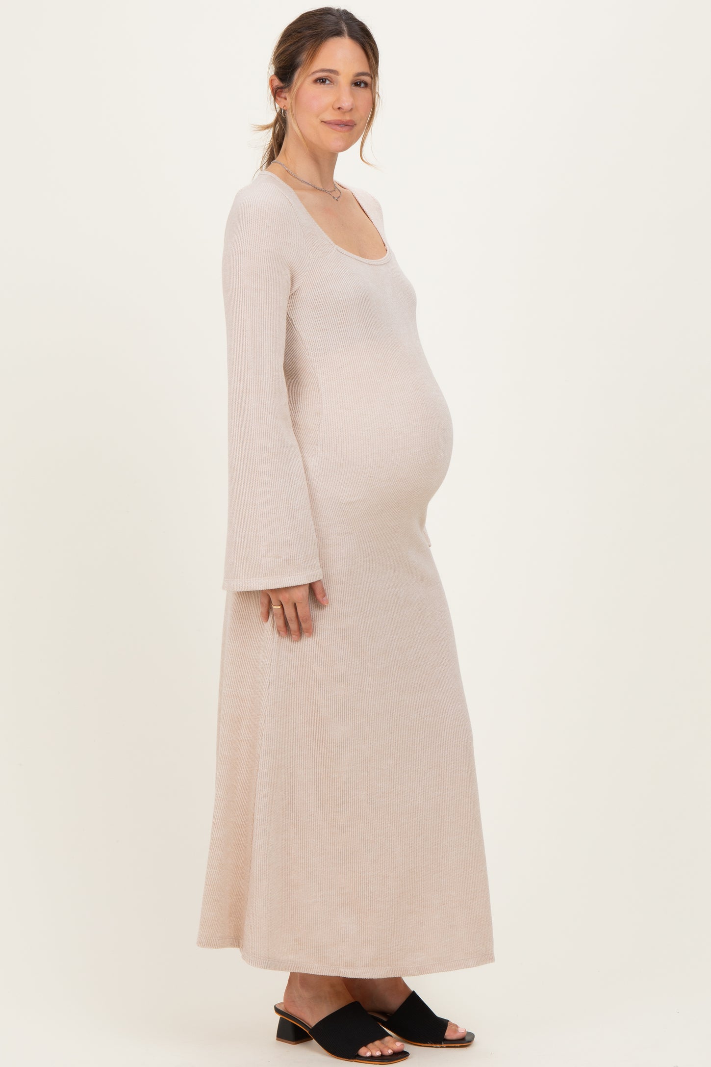 woman wearing a light pink ribbed maternity maxi dress with long sleeves and a visible baby bump