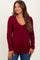woman wearing a burgundy long sleeve maternity top with a v-neck and button details, showing a baby bump