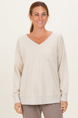 woman wearing a light beige oversized v-neck sweatshirt with a front pocket and relaxed fit