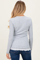 woman wearing a gray long sleeve maternity top with a scalloped hem, viewed from the back, paired with blue jeans