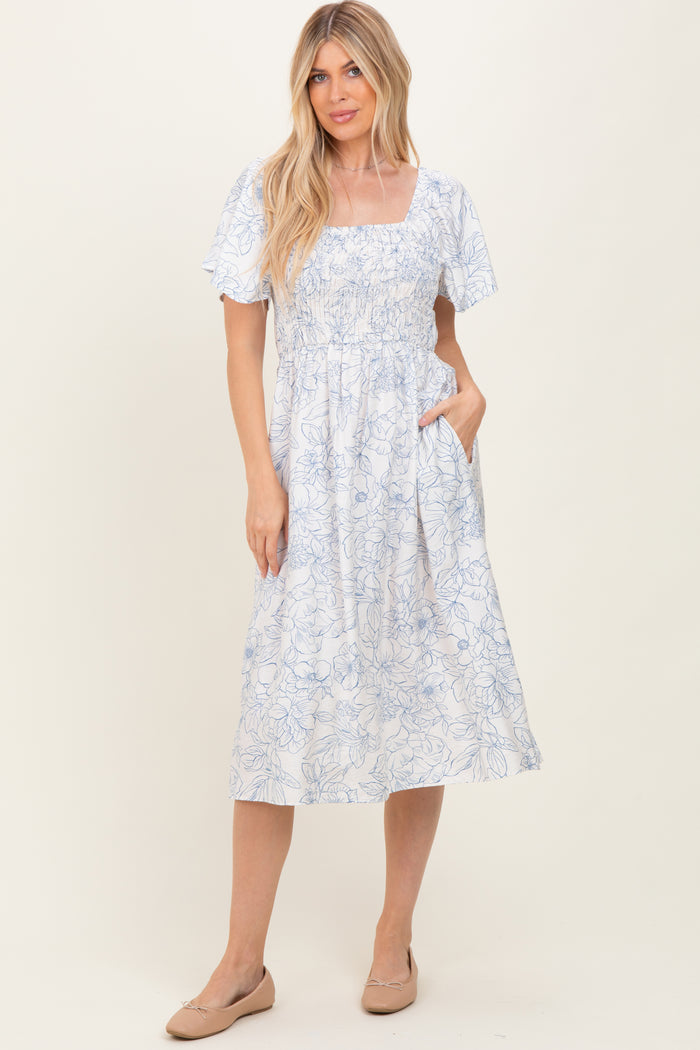 woman wearing a blue and white floral midi dress with short sleeves and pockets