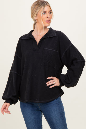 woman wearing a black oversized pullover with a collar and front pocket, styled with blue jeans