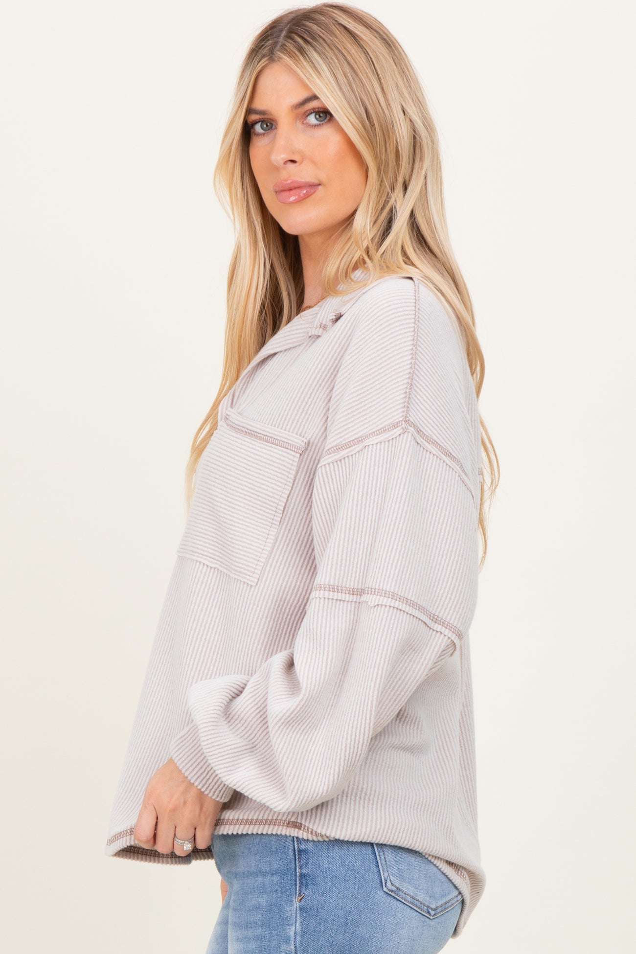 woman wearing a light beige striped oversized sweatshirt with pockets and long sleeves