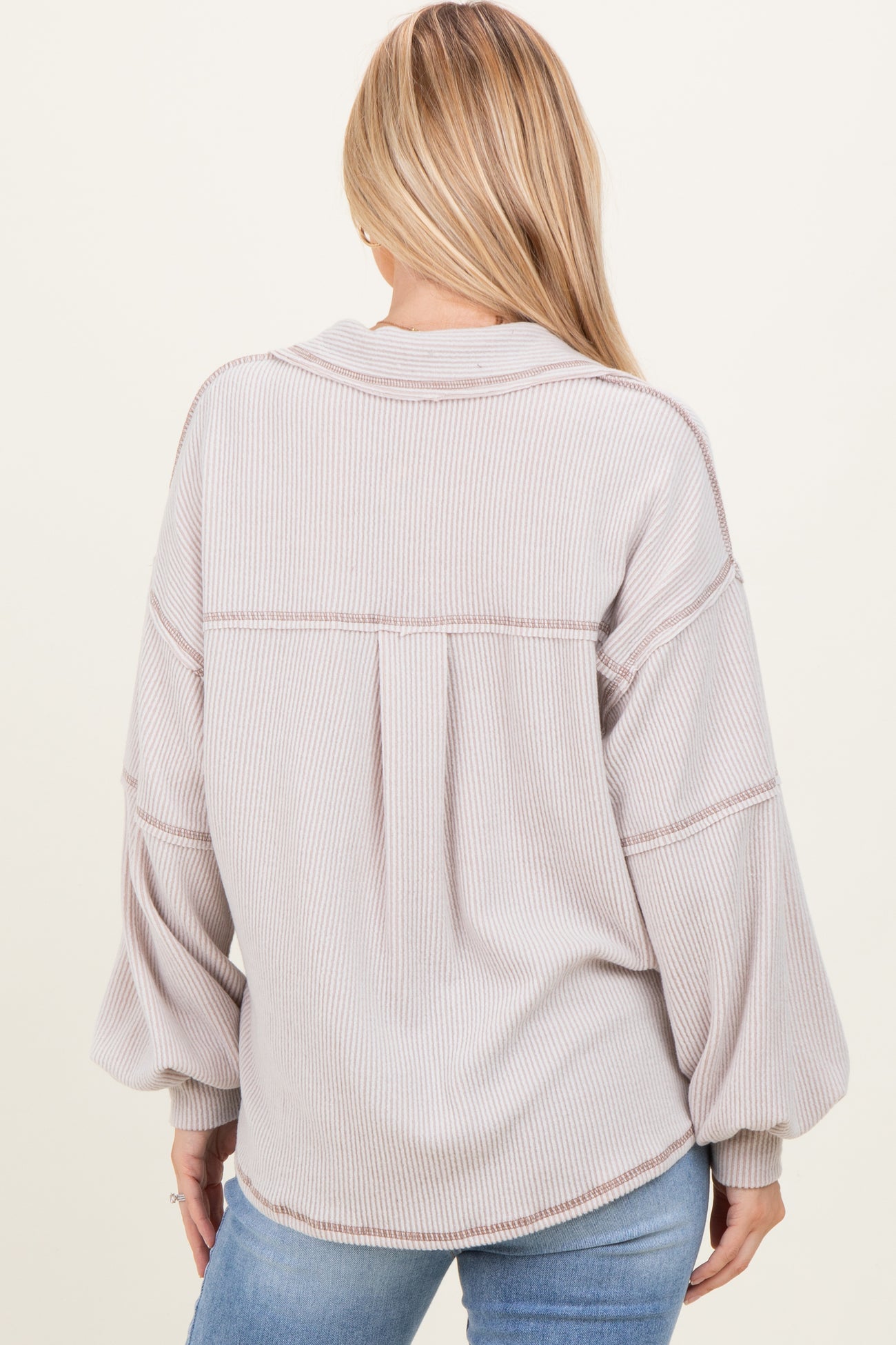 woman wearing a light taupe striped oversized sweater with balloon sleeves and a relaxed fit