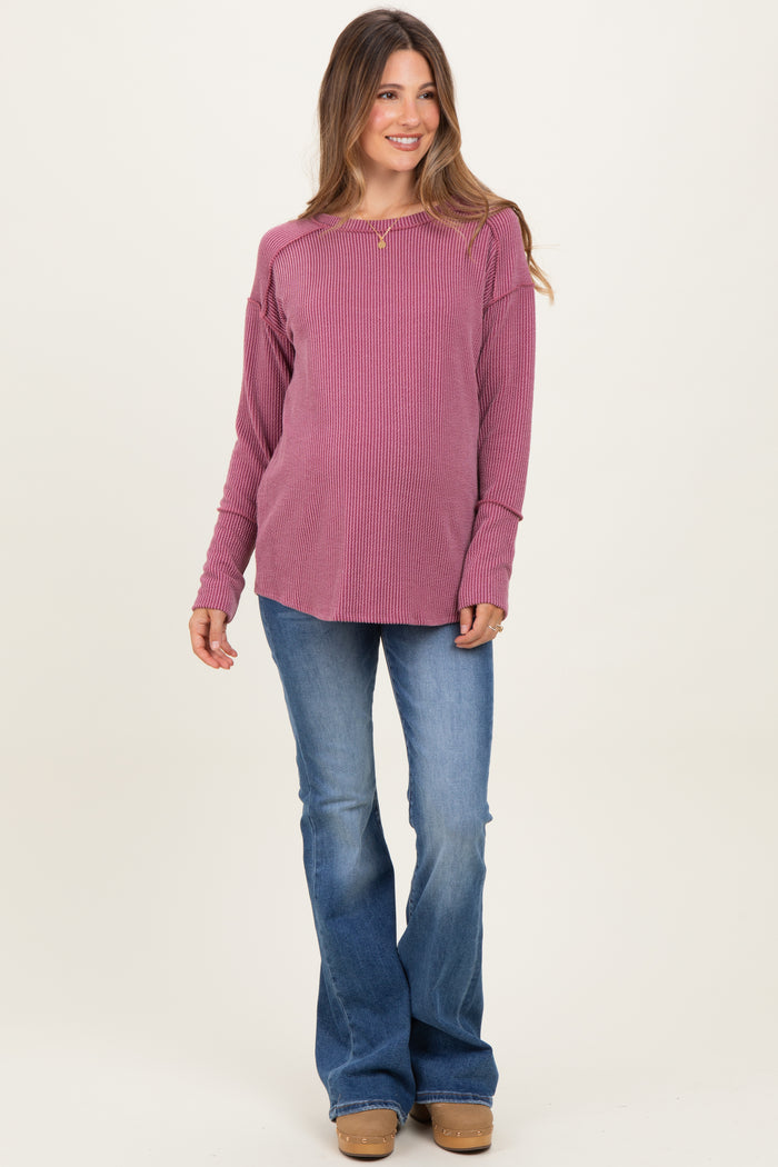 woman wearing a pink ribbed maternity top and flared jeans, showing a baby bump