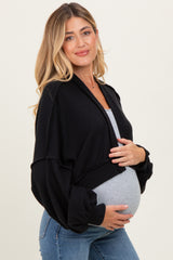woman wearing a black ribbed maternity cardigan over a gray top and holding her baby bump