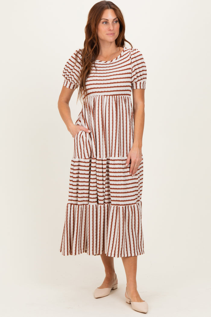 woman wearing a striped tiered midi dress with puff sleeves and pockets in neutral tones