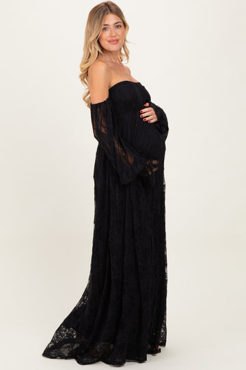 woman wearing a black lace off-the-shoulder maternity gown and holding her baby bump