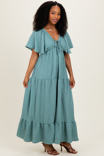 woman wearing a teal maxi dress with flutter sleeves and a tie front detail