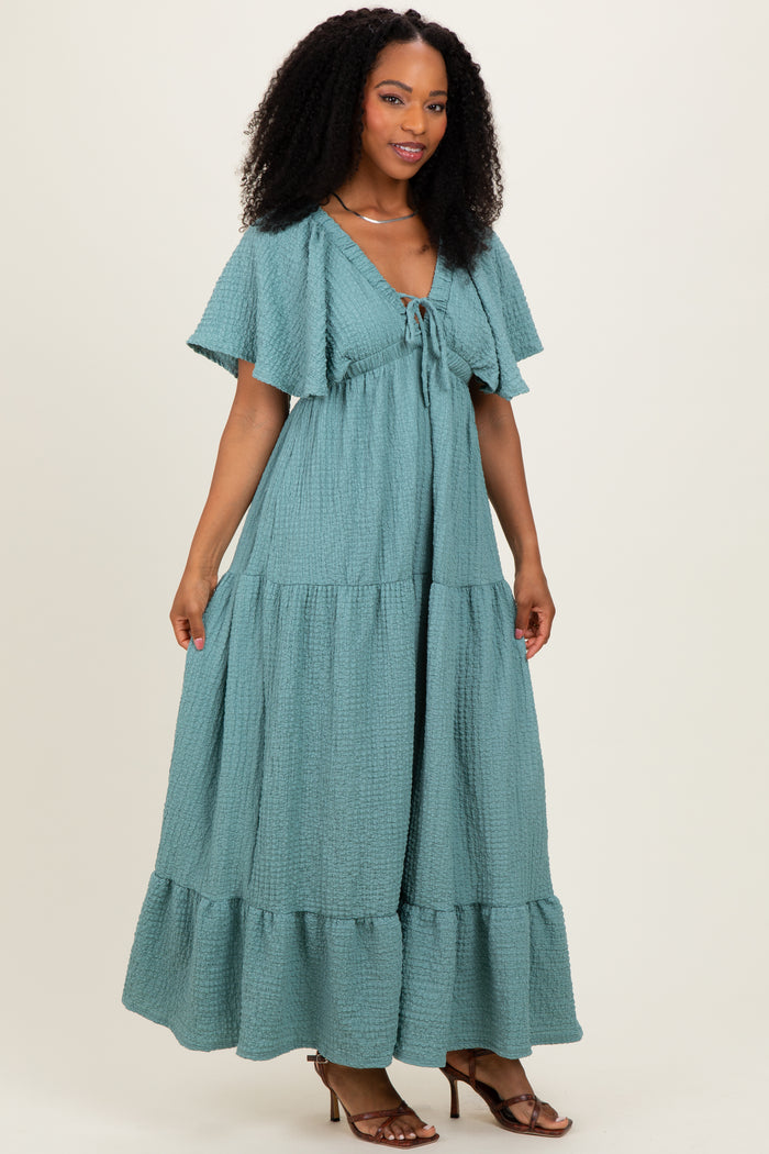 woman wearing a teal maxi dress with flutter sleeves and a tie front detail