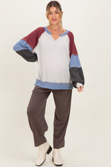 woman wearing a color-blocked maternity top with a v-neck and long sleeves, paired with gray wide-leg pants and a baby bump visible