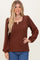woman wearing a brown ribbed long sleeve top with a scoop neckline and puff sleeves, smiling at the camera