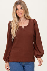 woman wearing a brown ribbed long sleeve top with a keyhole neckline and puffed sleeves