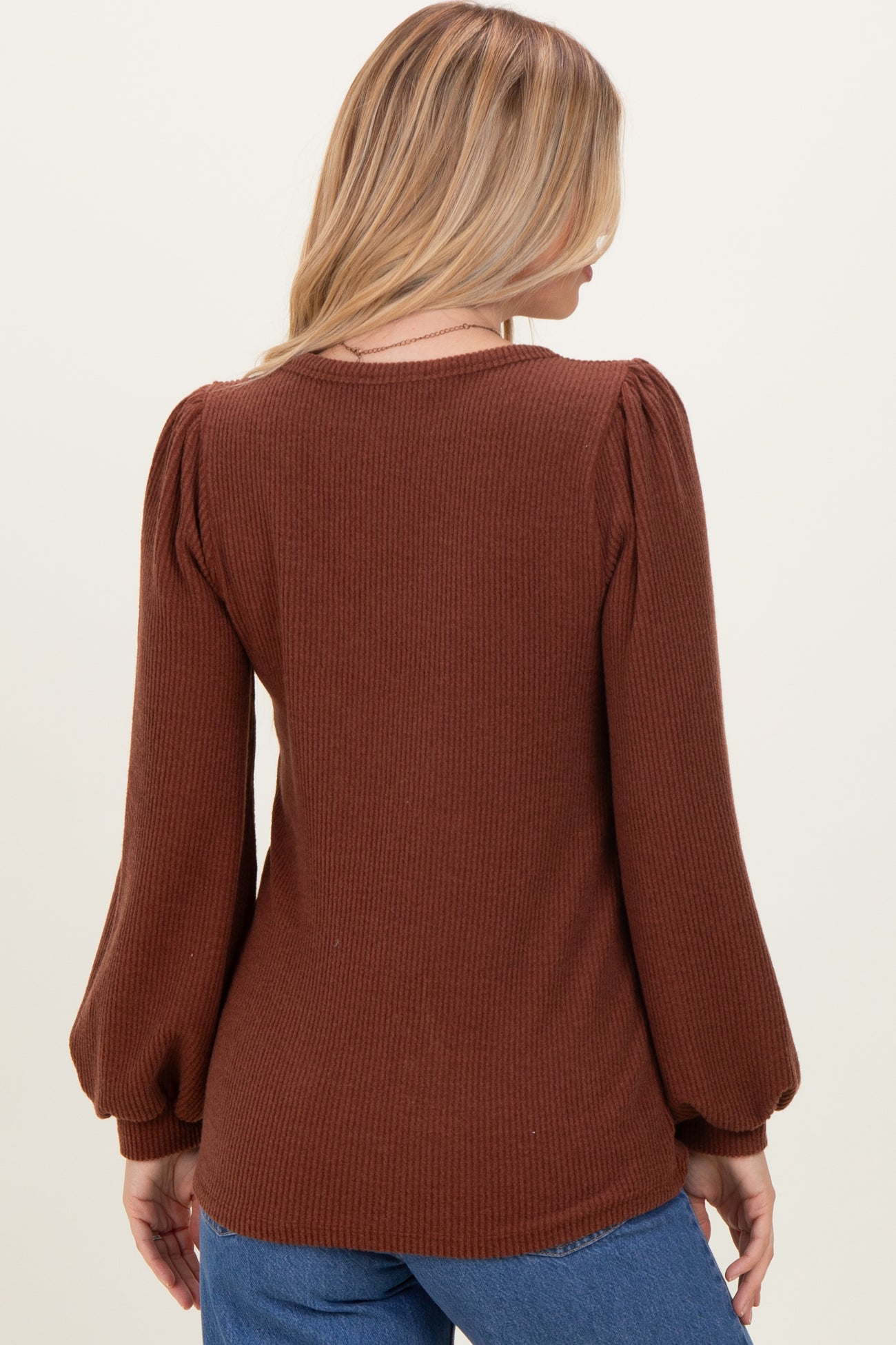 woman wearing a brown ribbed long sleeve top with puff sleeves, viewed from the back