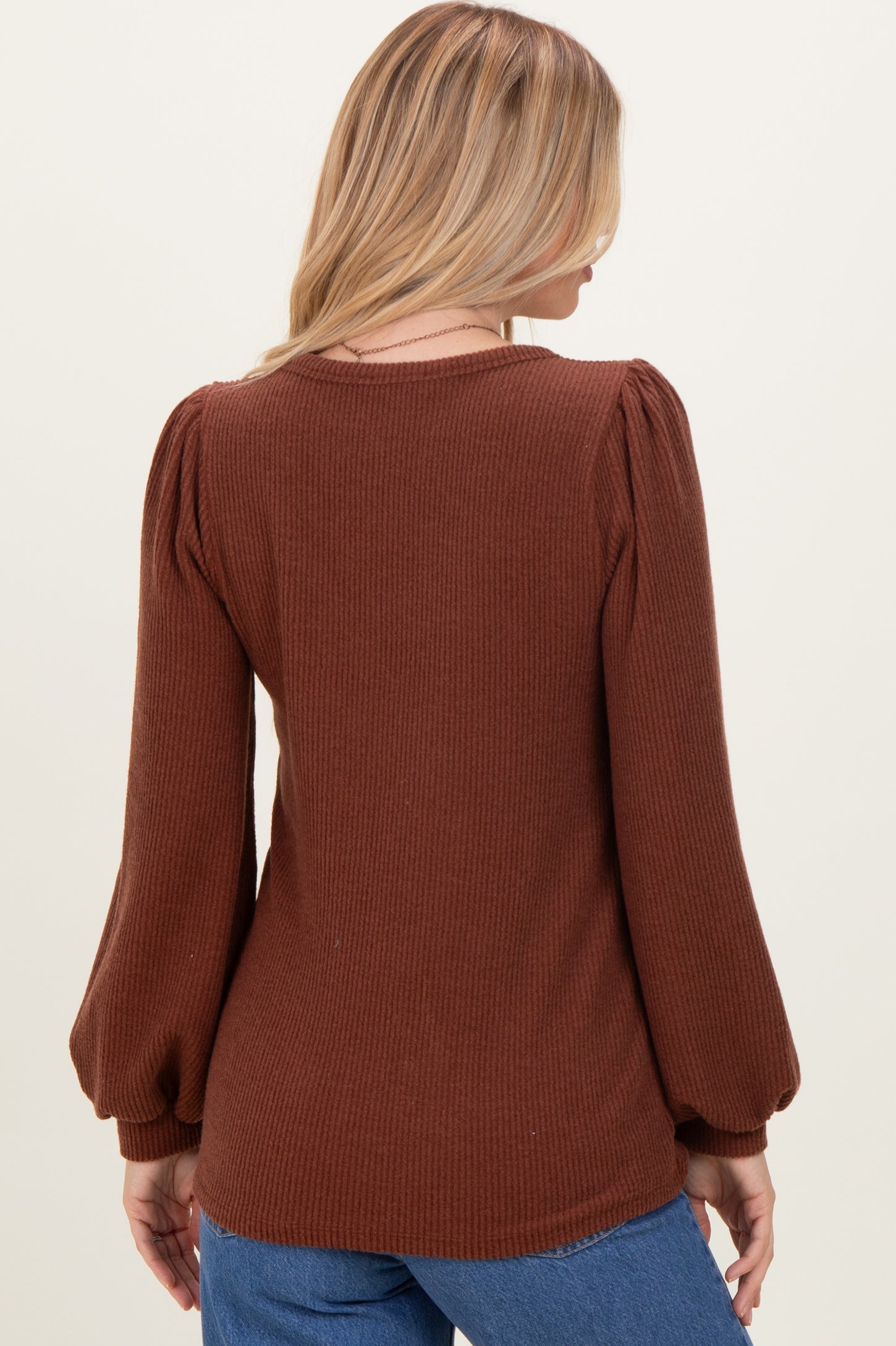 woman wearing a brown ribbed long sleeve top with puff sleeves, viewed from the back