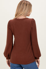 woman wearing a brown ribbed long sleeve top with puff sleeves, viewed from the back