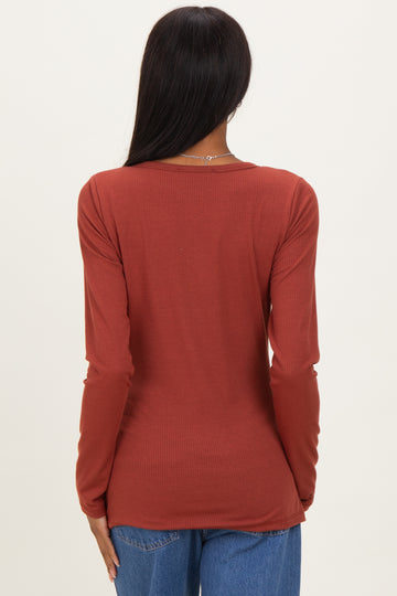 woman wearing a rust-colored long sleeve ribbed top, showing the back view with fitted style and round neckline