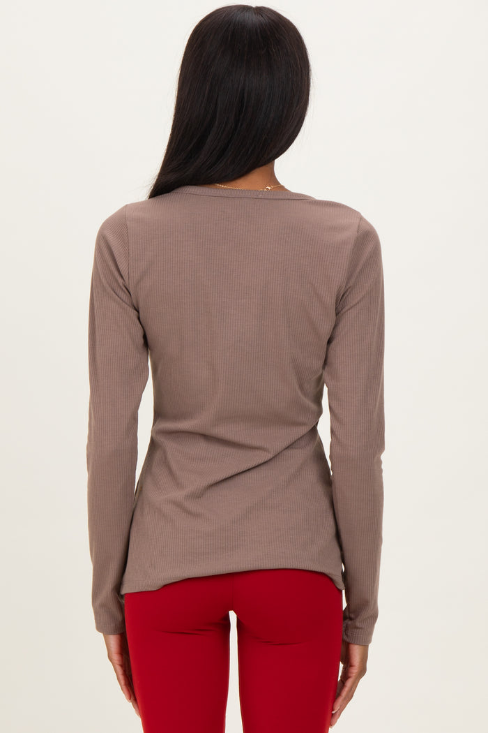 woman wearing a taupe long sleeve ribbed top and red leggings, shown from the back