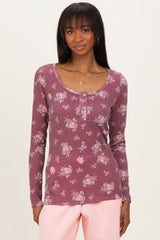 woman wearing a burgundy floral long sleeve scoop neck top with button details and ribbed texture