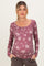 woman wearing a mauve floral maternity top with long sleeves and button details, showing her baby bump