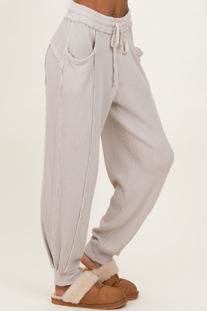 woman wearing light gray striped lounge pants with pockets and a drawstring waist, styled with cozy slippers