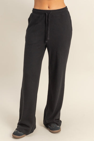 woman wearing black wide-leg lounge pants with a drawstring waist and two side pockets