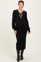 woman wearing a black long sleeve maternity dress with a keyhole detail and decorative bows, showcasing a baby bump