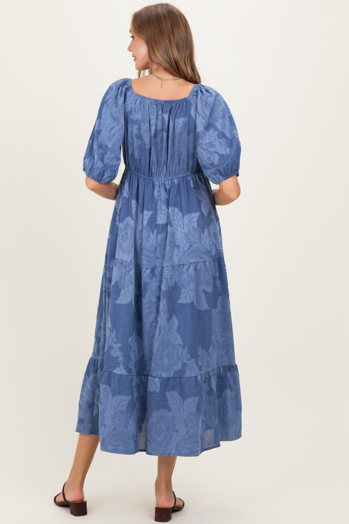 woman wearing a navy blue floral maternity maxi dress with puff sleeves and a tiered skirt, showing her baby bump