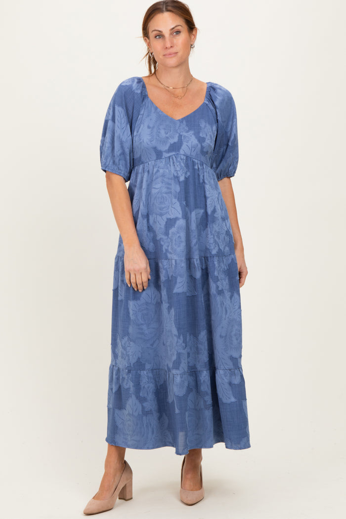 woman wearing a blue floral maxi dress with puff sleeves and a tiered skirt, styled with nude heels