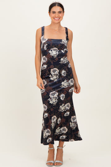 woman wearing a navy floral midi dress with square neckline and wide straps, standing and smiling
