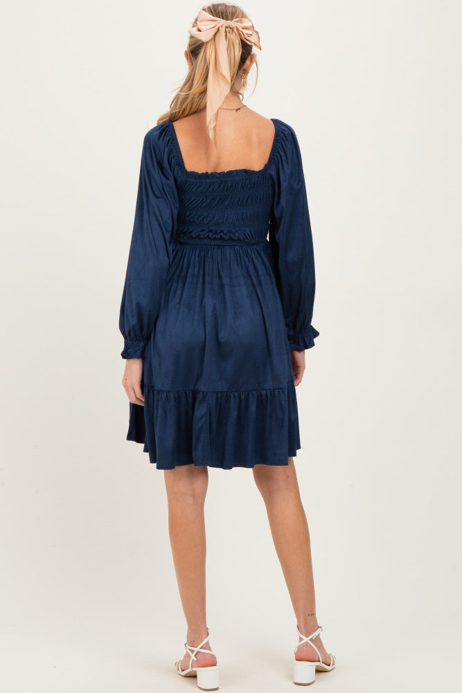 woman wearing a navy blue maternity dress with puff sleeves and a tiered skirt, showing a baby bump from the back