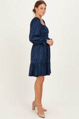 woman wearing a navy blue smocked dress with puff sleeves and a tiered ruffle hem, standing in profile with heels
