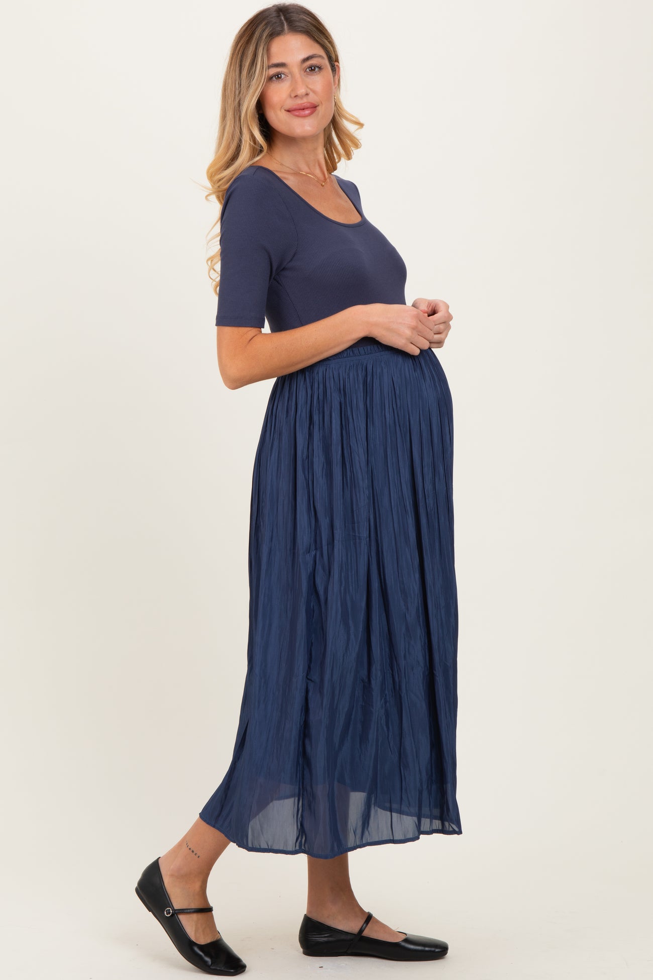 woman wearing a navy blue maternity dress with a fitted top and flowy skirt, showing her baby bump