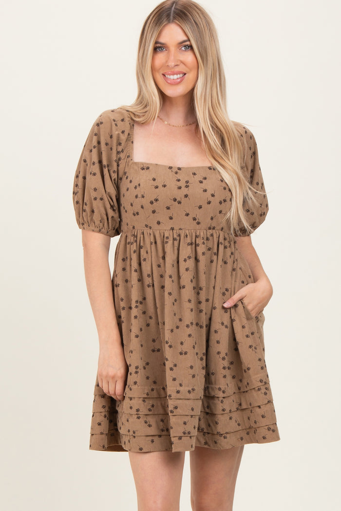 woman wearing a brown short puff sleeve dress with floral print and a square neckline, featuring pockets