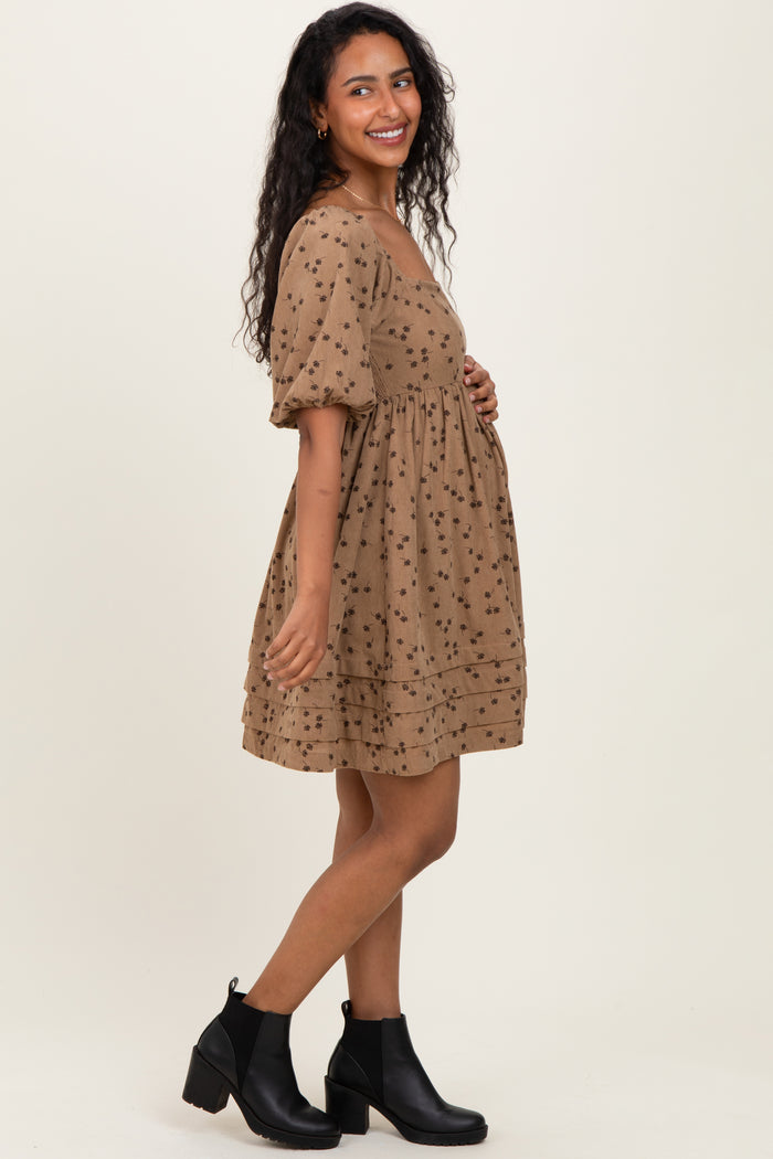 woman wearing a brown maternity dress with floral print and puff sleeves, showing her baby bump
