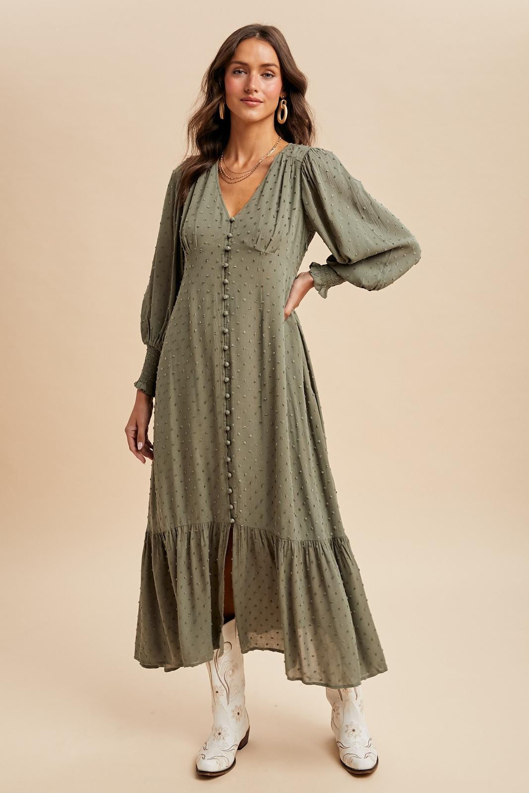 woman wearing an olive green long sleeve midi dress with a tiered skirt and button details, styled with white boots