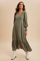 woman wearing an olive green long sleeve button-up dress with a tiered skirt and white cowboy boots