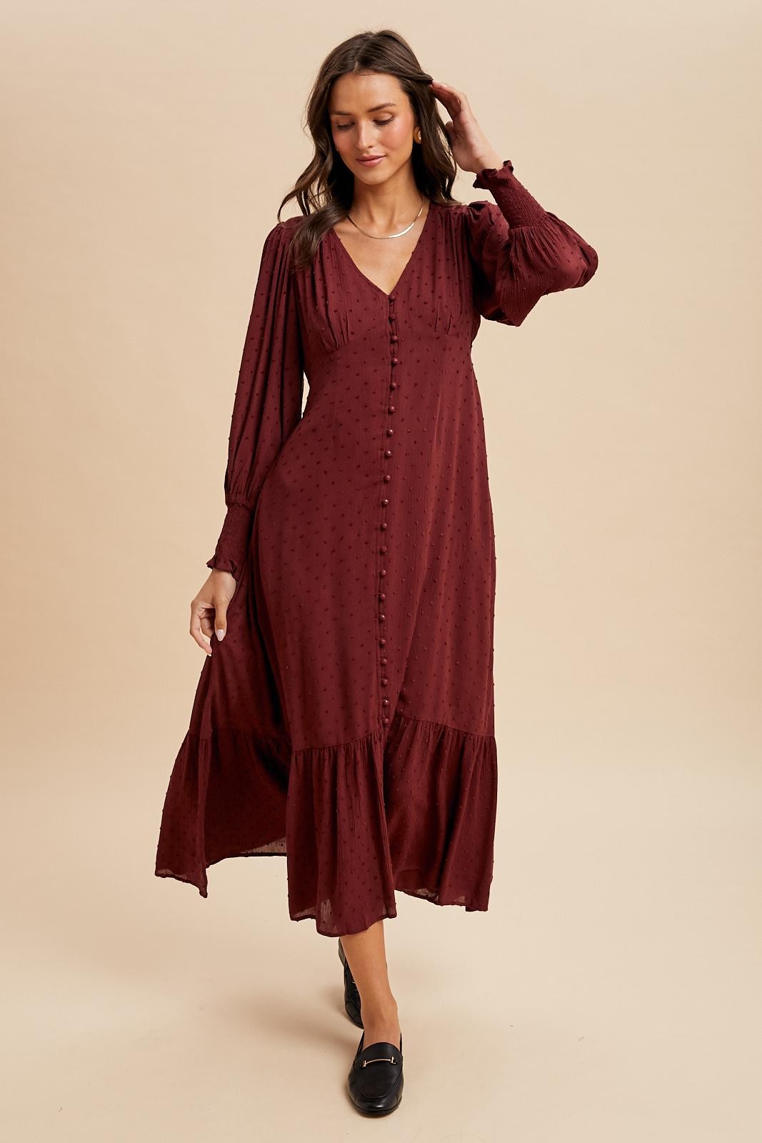 woman wearing a maroon long sleeve button-up dress with a tiered skirt and textured dot pattern