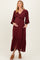 woman wearing a burgundy maternity dress with buttons, a tie waist, and long sleeves, showing a baby bump