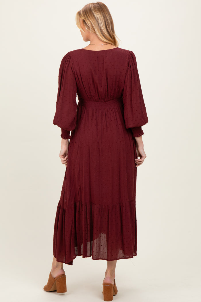 woman wearing a burgundy maternity dress with puff sleeves and a tiered hem, showing a baby bump from the back
