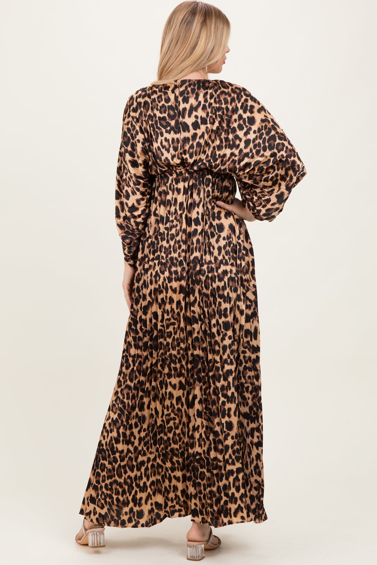 woman wearing a long leopard print maxi dress with gathered waist and long sleeves, view from the back