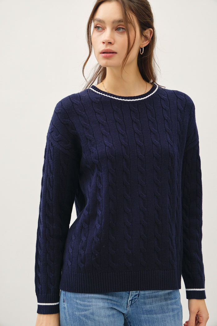 woman wearing a navy blue cable knit sweater with a contrasting collar detail and long sleeves