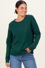 woman wearing a green cable knit sweater with a round neckline and relaxed fit, paired with denim jeans