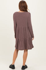 woman wearing a brown striped long sleeve tiered dress, standing with her back to the camera