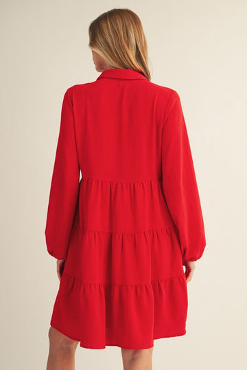 woman wearing a red tiered dress with long sleeves, shown from the back